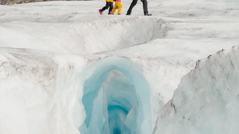 Meltwater pouring into a deep blue crevasse on the Athabasca Glacier with walkers above it